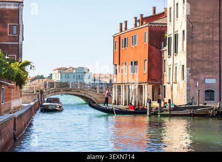 Traditionelle Gondel auf einem ruhigen venezianischen Kanal mit historischer Brücke in Venedig, Italien Stockfoto