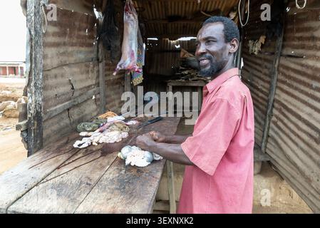Lächelnder Metzger steht neben Innereien auf einem Holztisch, Ghana Stockfoto