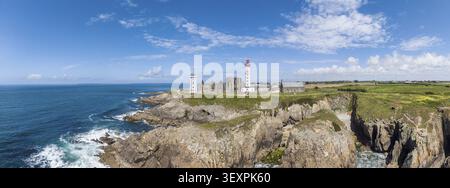 Aus der Vogelperspektive, Panorama des markanten rot-weißen Leuchtturms Phare de Saint-Mathieu an der bretonischen Küste neben den historischen Kirchenruinen der Stockfoto