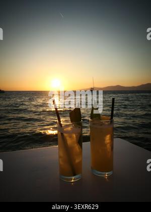 Cocktailgläser, die bei Sonnenuntergang auf dem Deck eines Kreuzfahrtschiffs klirren Stockfoto