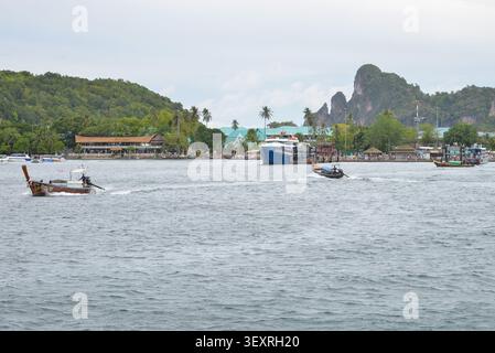 Phi Phi Inseln, Thailand – 18. Mai 2026: Boote vor Anker in der Bucht, umgeben von hohen Kalksteinklippen und tropischer Küste auf den Phi Phi Inseln Stockfoto