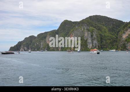 Phi Phi Inseln, Thailand – 18. Mai 2026: Boote vor Anker in der Bucht, umgeben von hohen Kalksteinklippen und tropischer Küste auf den Phi Phi Inseln Stockfoto
