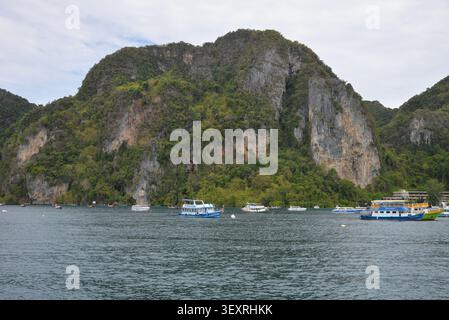 Phi Phi Inseln, Thailand – 18. Mai 2026: Boote vor Anker in der Bucht, umgeben von hohen Kalksteinklippen und tropischer Küste auf den Phi Phi Inseln Stockfoto