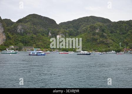 Phi Phi Inseln, Thailand – 18. Mai 2026: Boote vor Anker in der Bucht, umgeben von hohen Kalksteinklippen und tropischer Küste auf den Phi Phi Inseln Stockfoto