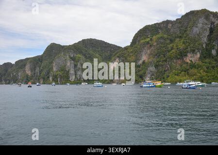 Phi Phi Inseln, Thailand – 18. Mai 2026: Boote vor Anker in der Bucht, umgeben von hohen Kalksteinklippen und tropischer Küste auf den Phi Phi Inseln Stockfoto