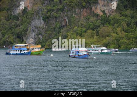Phi Phi Inseln, Thailand – 18. Mai 2026: Boote vor Anker in der Bucht, umgeben von hohen Kalksteinklippen und tropischer Küste auf den Phi Phi Inseln Stockfoto