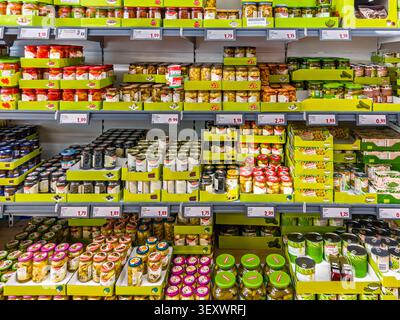 Italien - 30. Juni 2026: Supermarktregale mit Konserven und Glasgläsern mit Gemüse, Oliven, Pilzen und Gurken in einem Lidl-Einzelhandelsregal Stockfoto