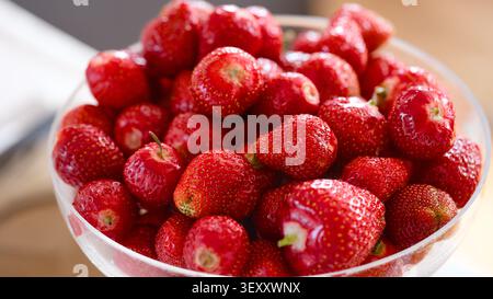 Eine Nahaufnahme einer Glasschale, gefüllt mit frischen Reifen roten Erdbeeren. Stockfoto