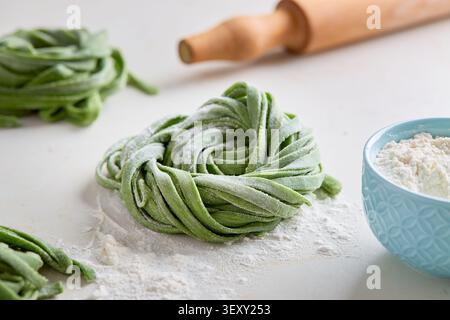 Frische hausgemachte Spinatnudeln auf hellem Hintergrund mit Mehl bestäubt Stockfoto
