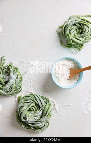 Frische hausgemachte Spinatnudeln auf hellem Hintergrund mit Mehl bestäubt Stockfoto