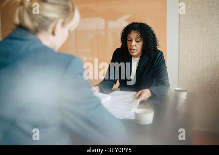 Reife Geschäftsfrau diskutiert Dokumente während eines Gesprächs mit einem Kollegen im Büro Stockfoto
