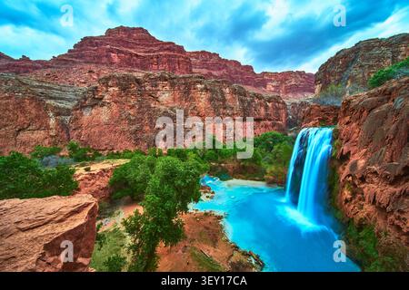 Der Havasu Falls Wasserfall Fließt In Den Turquoise Pool Zwischen Den Wänden Des Red Canyon Und Üppigen Bäumen Stockfoto