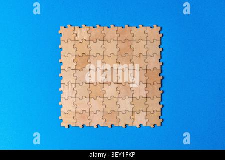 Puzzleteile aus Holz, die eine vollständige Einheit auf blauer Oberfläche bilden Stockfoto