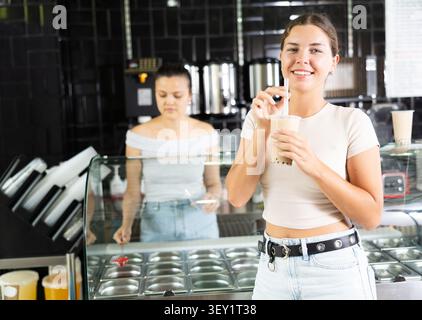 Junge Frau trinkt im Café Sprudeltee Stockfoto