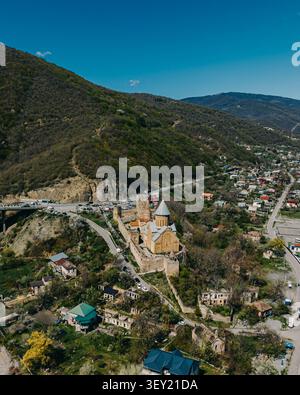 Aus der Vogelperspektive auf die Festung Ananuri mit dem umliegenden Dorf und der gewundenen Straße in den georgischen Bergen. Stockfoto