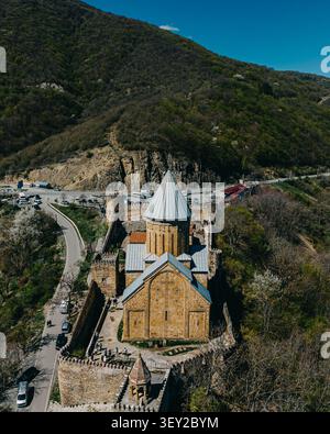 Erhöhte Luftaufnahme der Ananuri Kirche und Festung mit gewundenen Straßen und bewaldeten Hügeln in Georgia. Stockfoto