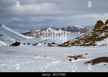 Der schneebedeckte High Atlas Pass in der Nähe von Telouet erstreckt sich zwischen schroffen Berghängen unter dunklen Winterwolken in Marokko. Stockfoto