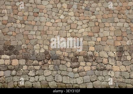strukturierte Steinmauer, Hintergrund mit Farbtönen von Beige bis Braun, abgerundete raue Steine in einer nahtlosen Mauer Stockfoto