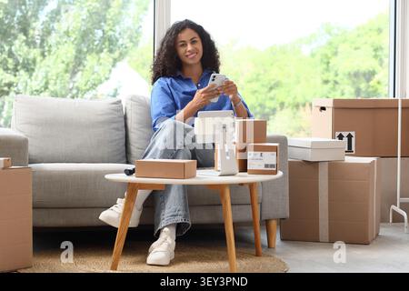 Junge Frau, die Online-Bestellungen zu Hause per Smartphone verwaltet Stockfoto