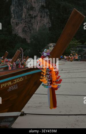 Phi Phi Inseln, Thailand – 18. Mai 2026: Ein traditionelles thailändisches Langboot mit farbenfrohen Blumengirlanden liegt am Ton Sai Beach mit Drama Stockfoto