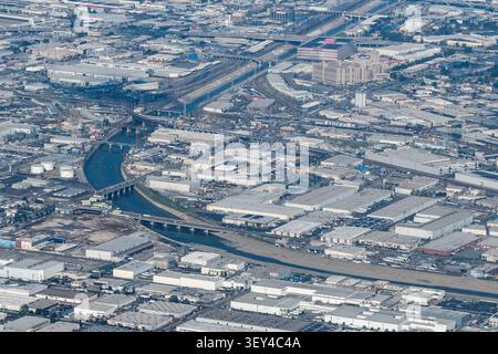 Blick aus der Vogelperspektive auf den Los Angeles River, der sich durch die Industriestadt Vernon, Kalifornien, schlängelt, mit Eisenbahnlinien, Brücken und Lagerhäusern Stockfoto