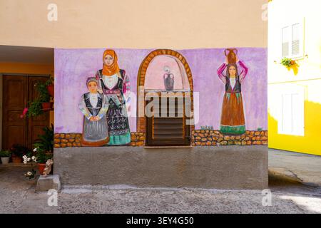 Straßenbild von Frauen in traditioneller sardischer Kleidung an einer Orgosolo-Hausfassade in Italien Stockfoto