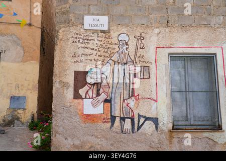 Stilisiertes Wandbild des Abtes des Heiligen Antonius mit einem Schwein und einem Porträt von Antonio Gramsci an einer Gebäudefassade in Orgosolo, Barbagia, Sardinien, Italien Stockfoto