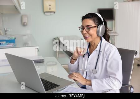 Glücklicher Arzt in Kopfhörern, der mit dem Patienten im Videogespräch spricht Stockfoto
