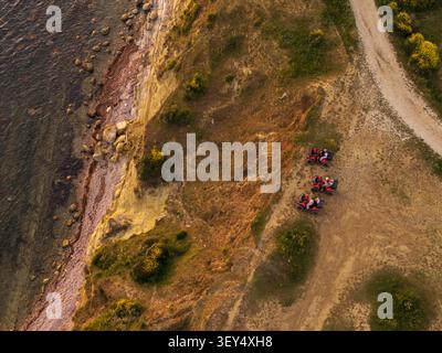 Aus der Vogelperspektive von drei Geländefahrzeugen, die auf einem unbefestigten Pfad entlang der Küstenklippen von Zvernec, Vlore County, Albanien, geparkt sind. Stockfoto