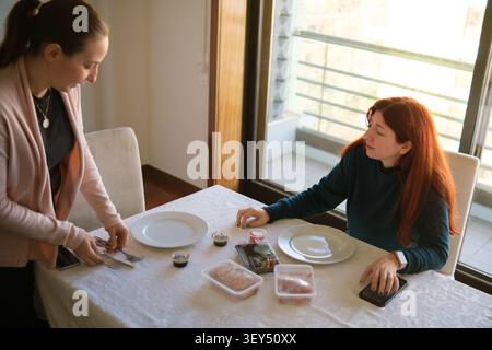 Frau, die einen Tisch für Sushi zum Mitnehmen mit einem Freund zu Hause auflegt Stockfoto