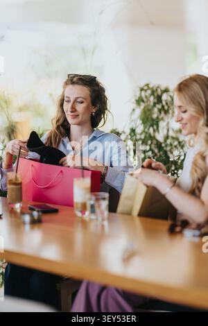 Zwei Freunde, die in einem Café einkaufen und Geschenke austauschen, während sie Kaffee und Unterhaltung genießen Stockfoto