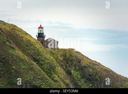 Point Sur Lighthouse auf einer Klippe mit bewölktem Himmel, das ein historisches Wahrzeichen von Big Sur über dem Pazifik zeigt. Stockfoto