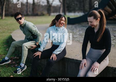 Drei Freunde, die sich nach einem Outdoor-Workout in einem Park Strecken und unterhalten Stockfoto