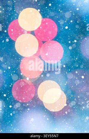 Vertikaler abstrakter festlicher Hintergrund mit roten und goldenen Bokeh-Lichtern auf einem tiefblauen Hintergrund mit sanft fallenden Schneeflocken. Warmes Leuchten Stockfoto