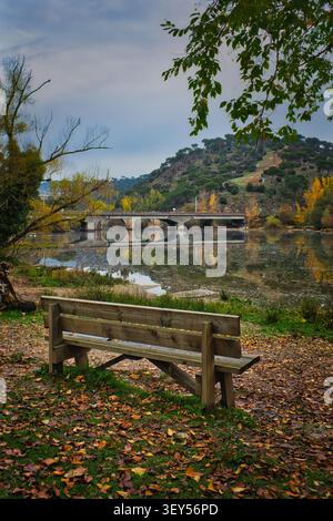 Herbstblick vom Erholungsgebiet La Depuradora auf dem Fluss Alberche mit Brücke San Juan im Hintergrund, in der Nähe von Pelayos de la Presa, Madrid, Spanien Stockfoto