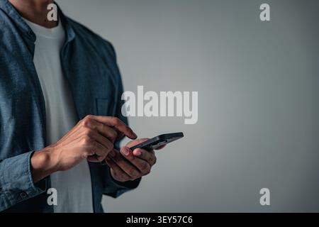 Die Handgeste eines Mannes, der mit einem Telefon posiert, ist ein modernes Geschäftszeichen, eine vielseitige Pose für technische Konzepte, die eine fokussierte und professionelle Pose zeigt Stockfoto