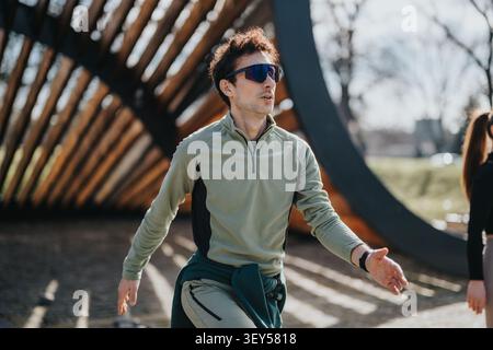 Junger Mann, der im Freien in einem Stadtpark läuft und Sonnenbrille und Sportkleidung trägt, um sich fit zu machen Stockfoto