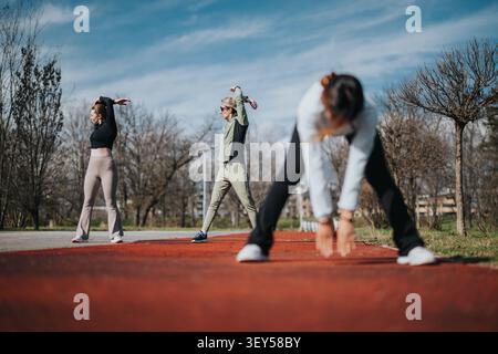 Junge Gruppe, die sich vor dem Training auf einer roten Laufstrecke im Freien ausdehnt Stockfoto