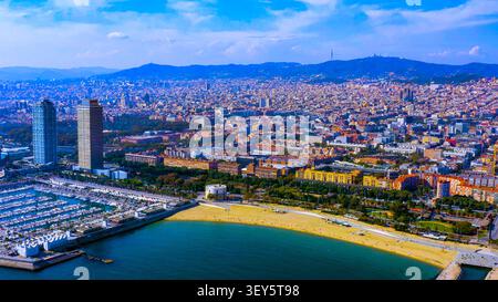 Blick aus der Vogelperspektive auf die Küste von Barcelona mit Port Olimpic Marina, Sandstrand und Twin Towers, Collserola Hügel am Horizont, Spanien Stockfoto