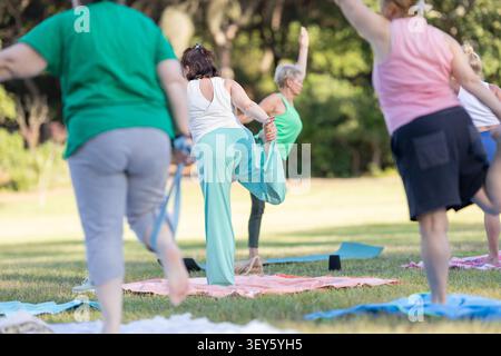 Eine Gruppe von Frauen, die im Park im Freien Yoga praktizieren Stockfoto