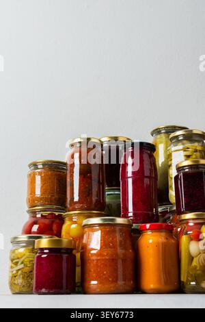 Canning ist eine häufige Aktivität in der Küche, da die Theke mit Gemüse und Obst gefüllte Gläser säumen. Diese Praxis hilft dabei, Lebensmittel für den Gewinn zu bewahren Stockfoto