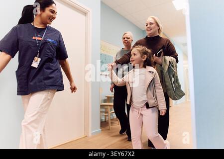 Lächelnde Ärztin begleitet Mädchen mit ihrer Familie zur Routineuntersuchung Stockfoto