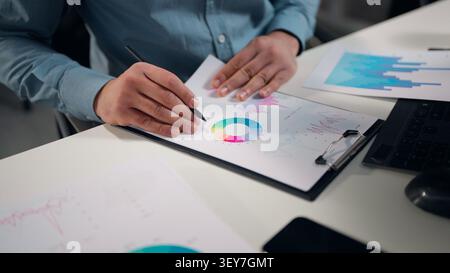 Nicht erkennbarer Geschäftsmann Analyse bunter Diagrammanalysen Papiere Freiansicht Nahaufnahme männliche Hände halten Stift unbekannter Geschäftsmann verwaltet Statistiken Stockfoto