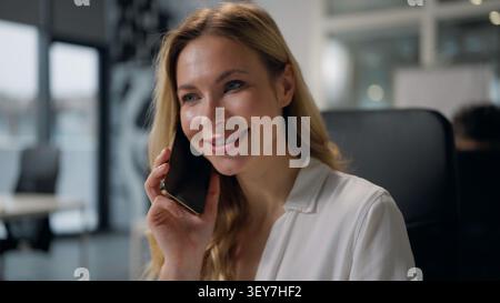 Glückliche Erwachsene kaukasische Geschäftsfrau spricht Handy im Firmenbüro lächelnd fröhliche Geschäftsfrau sprechen Smartphone kommunizieren Lächeln Mitte Stockfoto