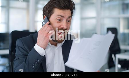Wütender kaukasischer reifer Geschäftsmann wütend schreiend im Handy mit Papieren Wut vor Fehlern Sprechen Sie, um einen Geschäftsmann mittleren Alters männlich anzurufen Stockfoto