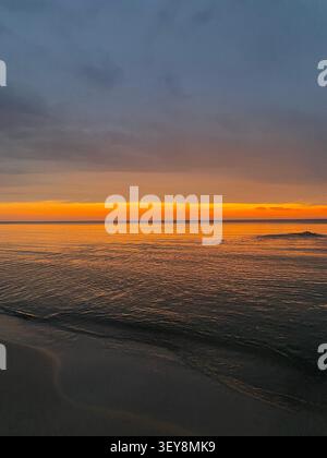 Farbenfroher Sonnenuntergang über dem Meer mit ruhigen Wellen Stockfoto