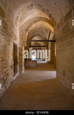 Blick von innen auf einen wunderschönen, bogenförmigen Steinkorridor mit warmem Sonnenlicht in der Zitadelle von Qaitbay in Alexandria, Ägypten. Stockfoto