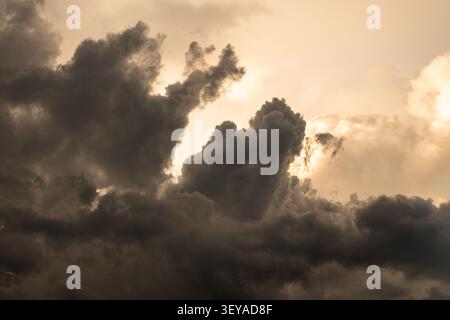 Überragende Sturmwolken, die von warmen Abendlichtern beleuchtet werden, Momente vor einem Sommergewitter in der Schweiz. Stockfoto