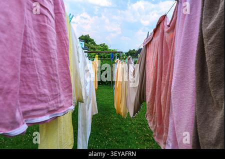 Bunte Kleidung und Handtücher hängen an einer Wäscheleine im Freien. Stockfoto