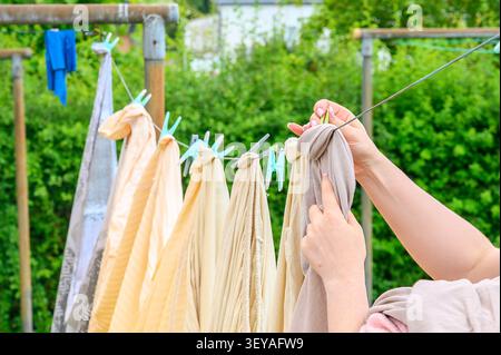 Frau, die frisch gewaschene Wäsche an einer Wäscheleine hängt. Stockfoto